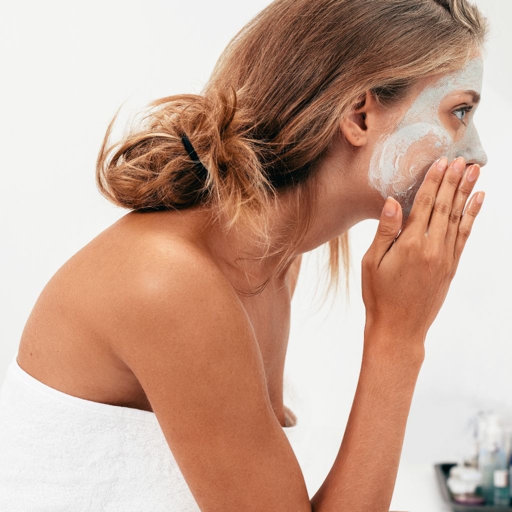 Girl applying Acne Stop Facial Mask by Estala Skincare to her face in circular motion.